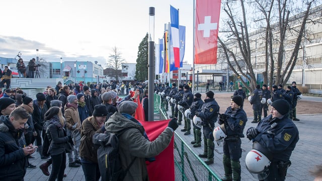 Pegida demonstriert: Man sieht einige Demonstranten, die Polizisten gegenüber stehen. Man sieht Fahnen von der Schweiz, Frankreich und Deutschland.