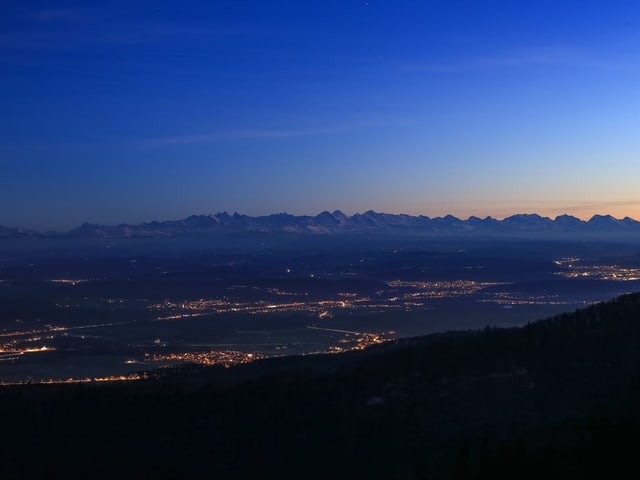 Blick ins Mittelland mit den Bergen im Hintergrund während der Nacht