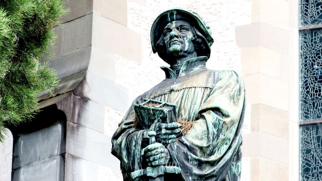 Ansicht der Zwingli-Statue in Zürich: Der Reformator hält ein Buch und ein Schwert in der Hand.