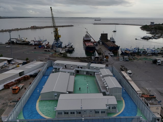 Luftansicht eines Hafens mit umliegenden Gebäuden und Booten am Pier.