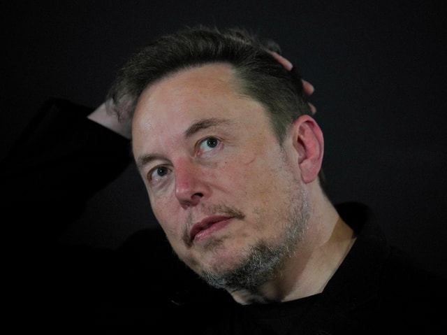 Elon Musk legt die Hand hinter den Kopf.