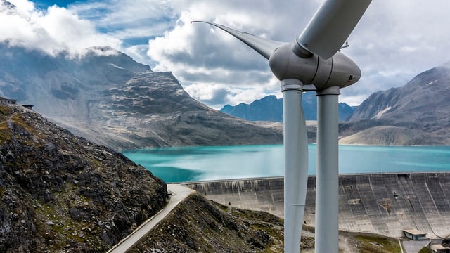 Im Vordergrund eine Windturbine, dahinter ein Stausee.