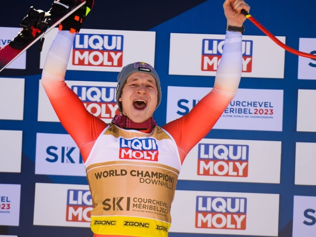 Marco Odermatt streckt beim Jubel auf dem Podium seine Skier in die Höhe