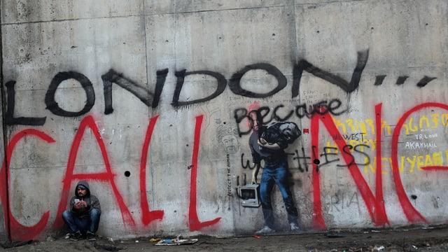 Mann sitzt vor Wand mit Grafitti «London Calling»