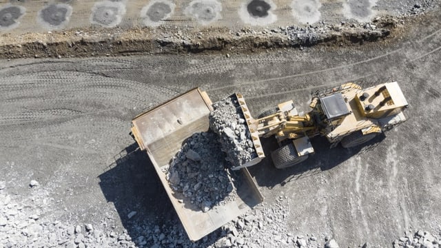 Ein Bagger belaedt einen Muldenkipper mit Steinen im Steinbruch eines Holcim Zementwerks in Untervaz,