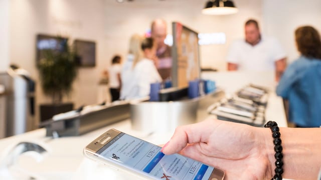 Eine Frau schaut sich ein Handy an in einem Laden. 