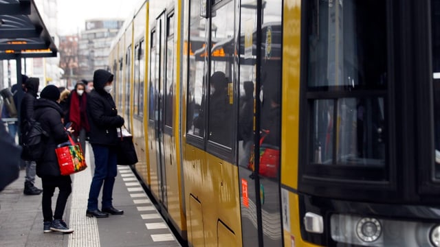 Pendler steigen mit Masken in eine Bahn ein.