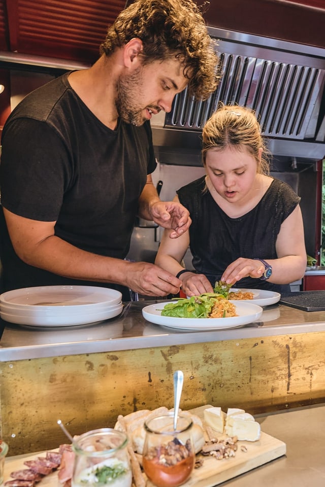 Ein Mann und eine Frau drapieren einen Salatteller.