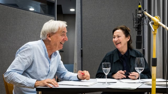 Charlotte Schwab und  Ueli Jäggi sitzen und lachen im Hörspielstudio bei den Aufnahmen von Hunkeler in der Wildnis. 