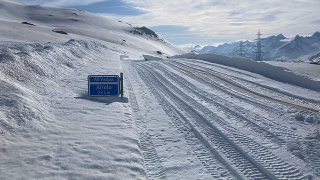 Ein Strassenschild welches knapp durch die Schneedecke ragt.