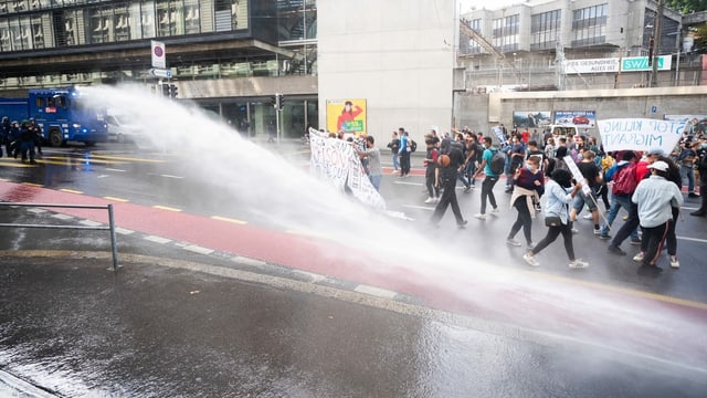 People are splashed by water cannons.