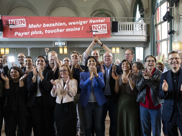 Gruppe applaudiert vor Banner mit Slogan gegen Rentenkürzungen.