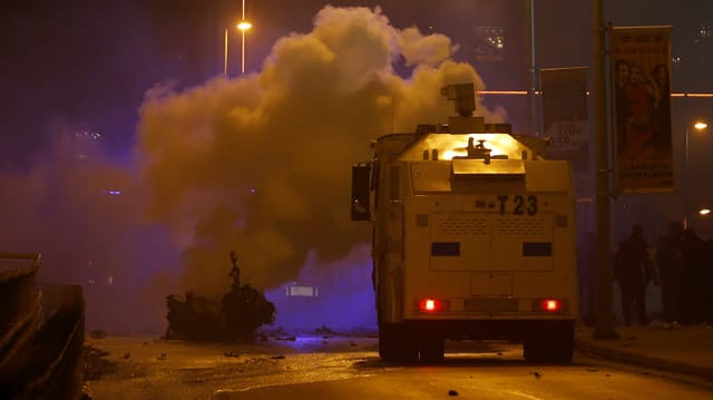 Feuerwehrfahrzeug vor rauchenden Autotrümmern.