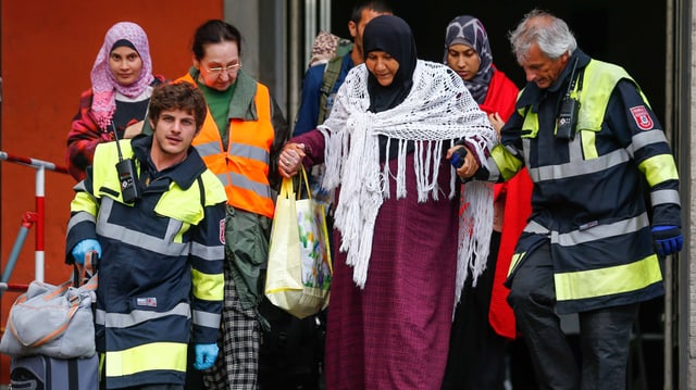 Am Bahnhof München helfen Helfer Flüchtlingen aus dem Zug zu steigen