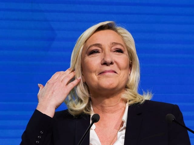 Marine Le Pen steht lächelnd vor einem Mikrofon.