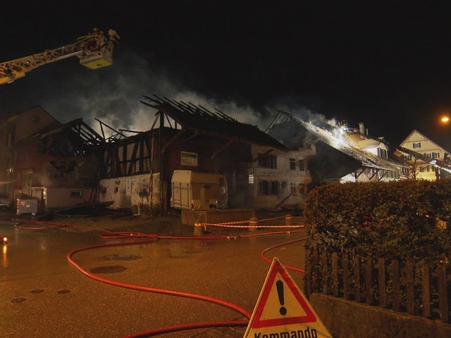 Bild eines der durch den Brand in Elgg beschädigten Gebäude. Davor ein Feuerwehrkran und ein Triopan auf der Strasse.