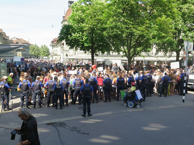 Police officers form a chain and push the crowd back. 