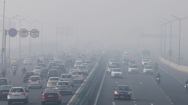 Verkehrsreiche Strasse mit Autos und Geschwindigkeitsbegrenzungsschildern im Nebel.