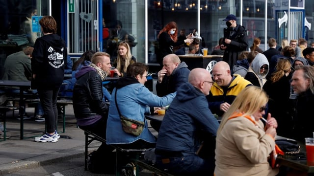 Menschen sitzen draussen in einer Bar.