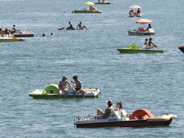 Menschen auf Tretbooten im Wasser.