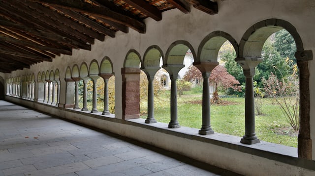 Ein kreuzgang mir vielen Bögen. Durch die Bögen hindurch ist der Klostergarten zu sehen.