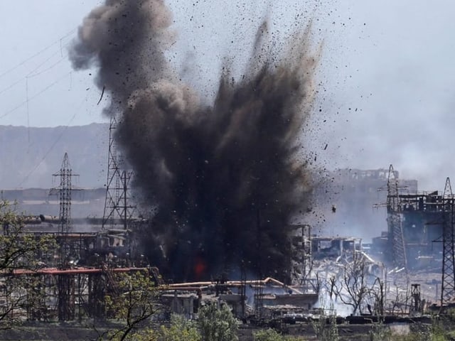 Eine Explosion auf dem Gelände des Stahlwerks wirbelt Dreck auf.