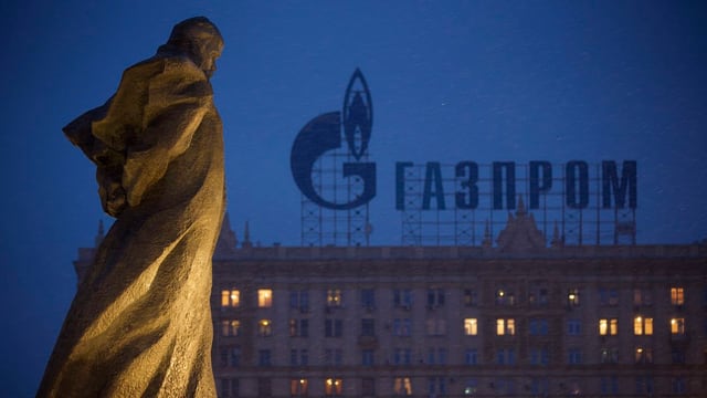 Schriftzug des russischen Gasanbieters Gazprom auf einem Gebäude in Moskau, links vorne eine Statue des Schriftstellers Taras Schewtschenko.