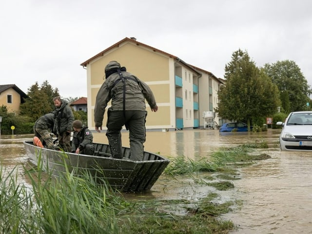 Männer in einem Boot retten Menschen während einer Überschwemmung.