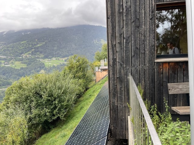 Eine Hauswand mit einer kleinen Solaranlage davor.