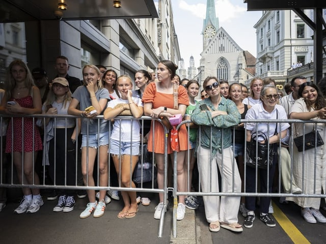 Menschenmenge hinter einer Absperrung in einer Stadt.