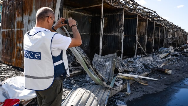 Ein OSZE-Beobachter fotografiert Bombenschäden in Donezk.