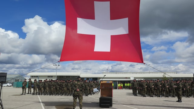 Schweizer Fahne und Soldaten auf Flugplatz.