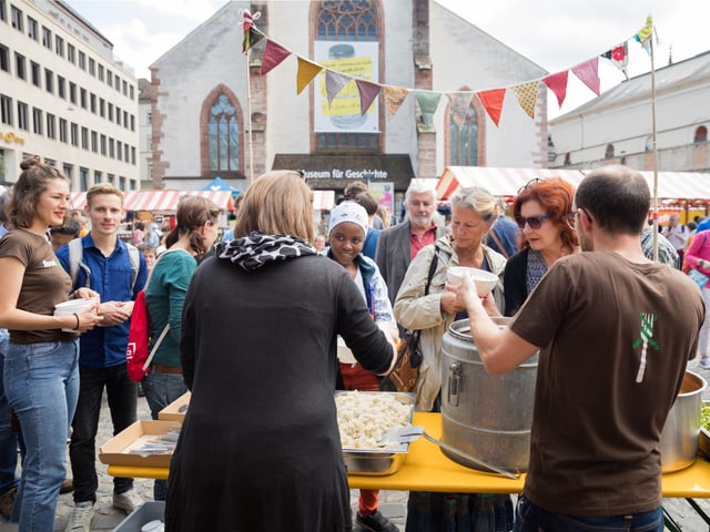 Leute stehen an am Stand von Foodsharing Basel und warten auf Essen.