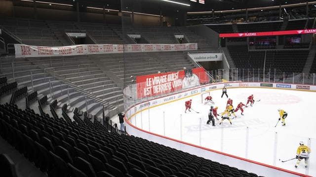 Ice hockey players play in front of empty stands.