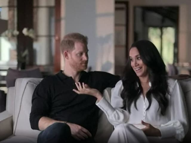 Szene aus der Netflixserie von Harry und Meghan, beide sitzen auf dem Sofa und unterhalten sich.