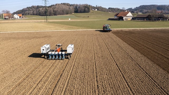 Ein Traktor auf einem gepflügtem Feld.