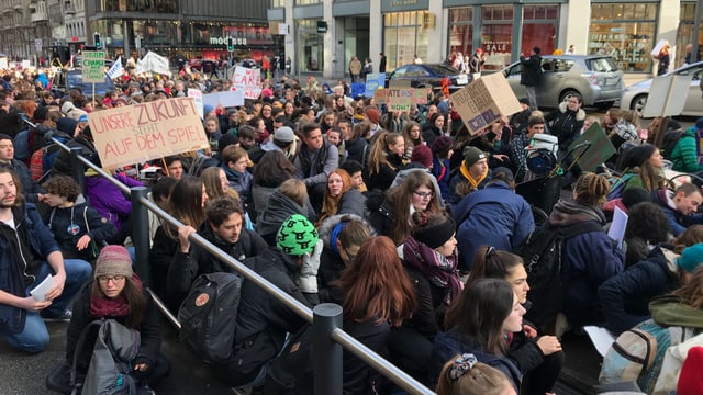 Eine Gruppe von Schülerinnen und Schülern sitzt auf der Bahnhofstrasse.