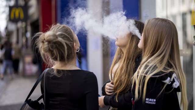 Drei junge weibliche Personen vapen