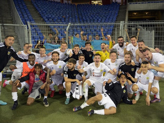 Fussballmannschaft jubelt vor leeren Tribünen.