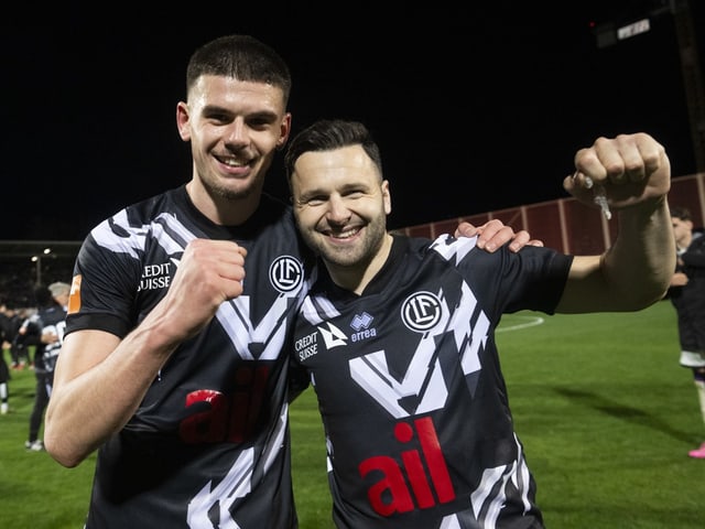 Zwei Fussballspieler feiern auf dem Spielfeld.