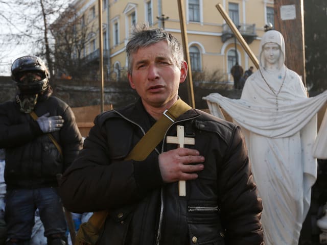 Hier beten Bewohner der Hauptstadt für den Frieden im Land, sie halten ein Kreuz in der Hand. 