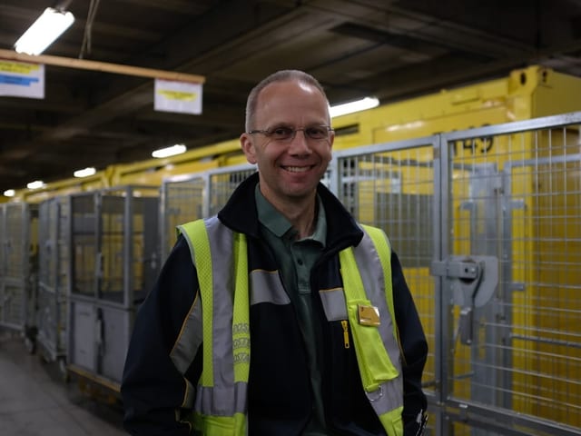 Thomas Sigrist, Mitarbeiter der Post, steht vor einem Paket-Zug.