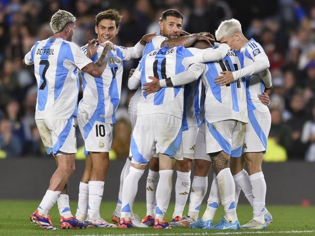 Argentinische Fussballspieler umarmen sich im Trikot der Nationalmannschaft.