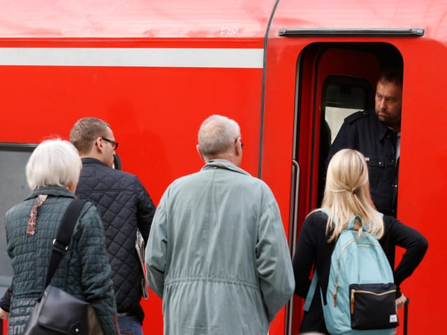 Bahnreisende im Gespräch mit einem Lokführer 