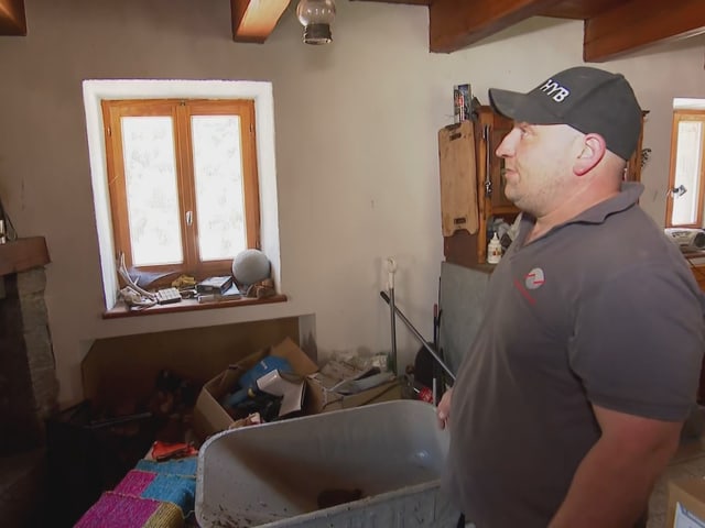 Ein Mann in einem unaufgeräumten Raum mit Fenster.