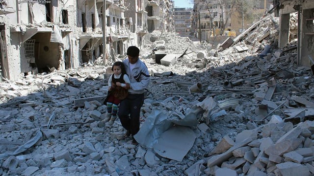 Ein Vater trägt seine Tochter durch die Trümmer der Stadt Aleppo. 