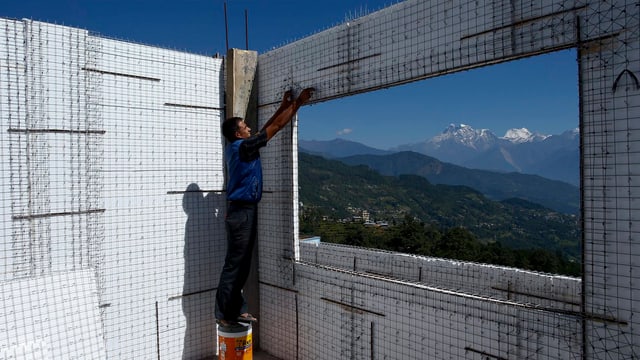 Ein Arbeiter erstellt an einem neuen Haus in Nepal eine Wand aus Karbon, um künftig vor Erdbeben besser geschützt zu sein. (keystone)