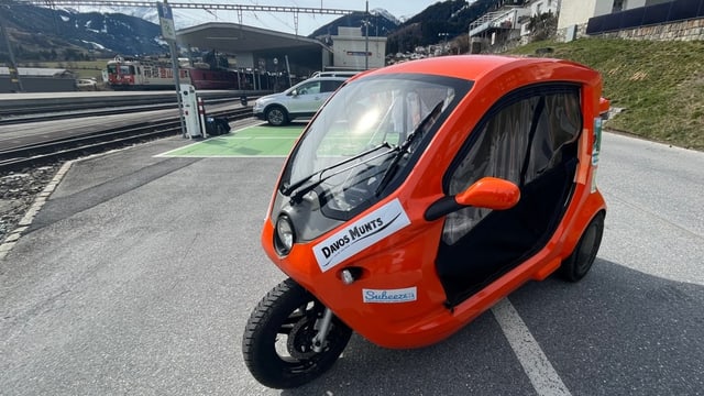 Ein oranges E-Tuk-Tuk steht am Bahnhof Disentis bereit.