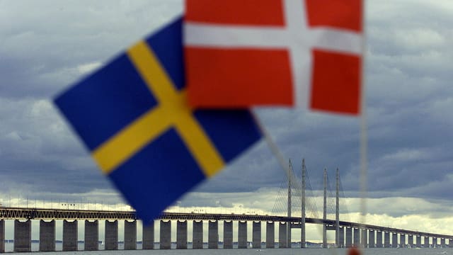 Schwedische und dänische Flaggen, dahinter die Öresund-Brücke. 