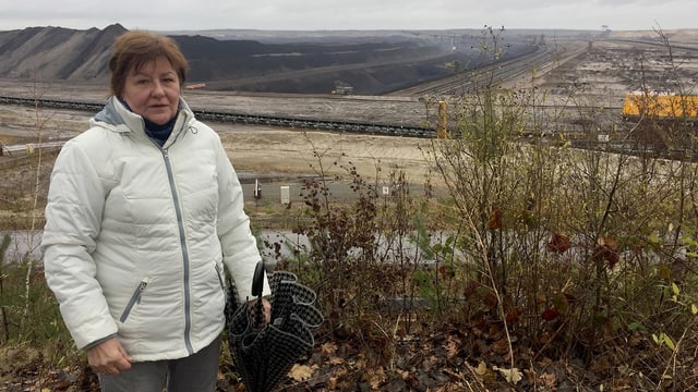 Eine Frau vor einer öden, zerfurchten Landschaft.